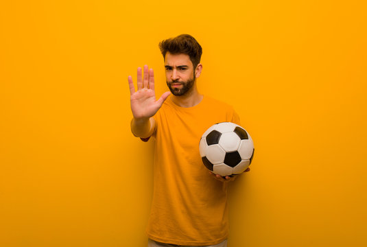 Young soccer player man putting hand in front