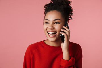 Amazing happy excited young african woman posing isolated over pink wall background talking by...