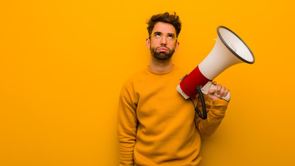 Young man holding a megaphone tired and bored