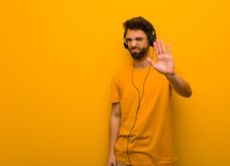 Young man listening to music putting hand in front