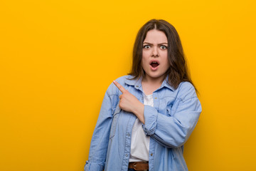 Fototapeta premium Young curvy plus size woman pointing to the side