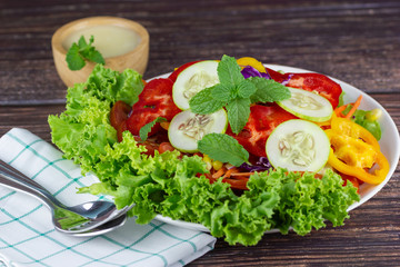 Close up A green salad is a dish of a mixture of small vegetables, Cucumbers fragrant vegetables tomatoes peppers corn carrots on wood table.