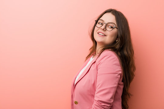 Young plus size business caucasian woman looks aside smiling, cheerful and pleasant.
