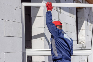 home construction loader worker carries a platic window for installation repairs