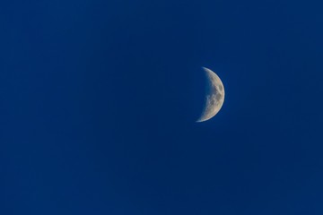 Obraz na płótnie Canvas White half-moon on dark blue sky at night.