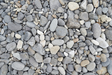 Texture of gray oval pebble stones next to the sea. Close-up