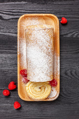Ciasto - rolada biszkoptowa z kremem mascarpone na czarnym drewnianym blacie © Grzej