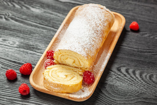 Ciasto - rolada biszkoptowa z kremem mascarpone na czarnym drewnianym blacie