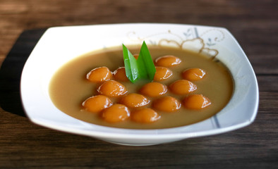 Biji salak on wood background. Biji salak is sweet potato dumplings with coconut sauce. Popular dessert in Indonesia or to break the fast.