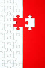 White puzzle pieces on a red background separated