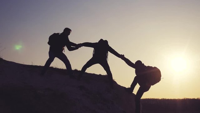 lifestyle teamwork help business travel silhouette concept. group of tourists lends a helping hand climb the cliffs mountains. people climbers climb to the top overcoming hardships the path to victory