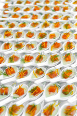 Celebration catering, small canapes of red fish - trout or salmon, in white portion bowls, side view, large amounts, daylight