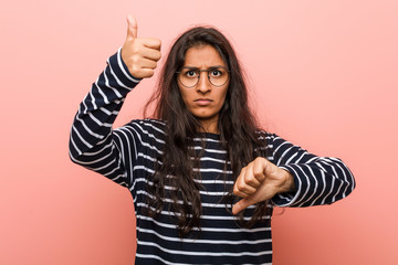 Young intellectual indian woman showing thumbs up and thumbs down, difficult choose concept