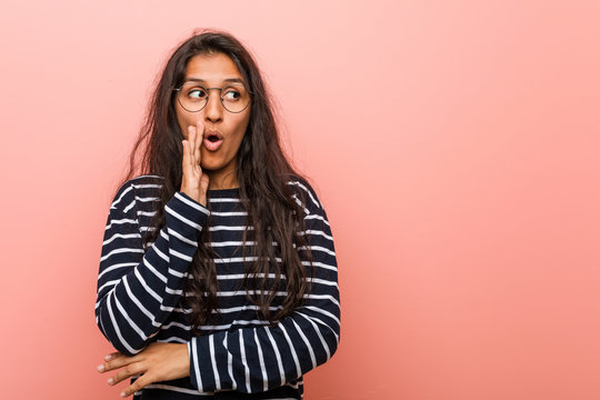 Young intellectual indian woman is saying a secret hot braking news and looking aside