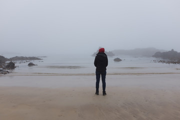 Woman looking at ocean back to camera, cold day