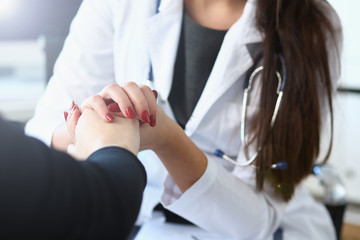 Young female doctor holds sick patient by hand expressing condolences and sympathy reports bad news about loss of loved ones due to cancer deadly aids disease and says we can handle support concept.