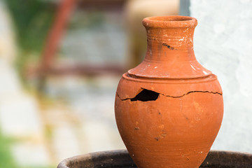 Broken clay jug with large hole and crack.