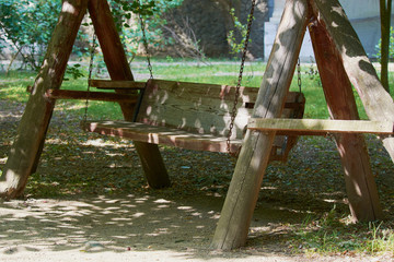 Old wooden swing on an iron chain in park.