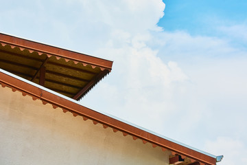 Obraz premium Large lumber building roof against blue sky with clouds.