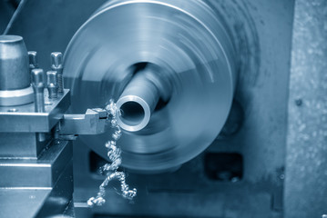 The lathe machine cutting the metal tube parts. The metal working manufacturing process.