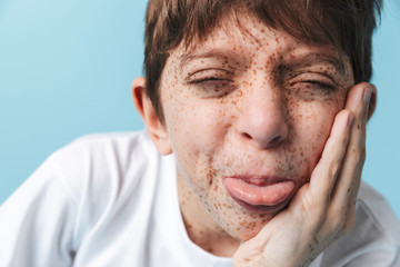 Obraz premium Portrait closeup of cheerful beautiful boy 10-12y with freckles wearing white casual t-shirt smiling at camera