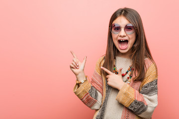 Little hippie girl pointing with forefingers to a copy space, expressing excitement and desire.