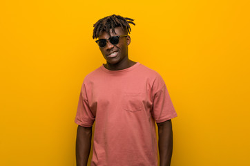 Young casual black man wearing sunglasses winking, funny, friendly and carefree.