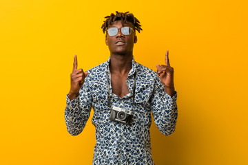 Young black rasta man wearing a vacation look indicates with both fore fingers up showing a blank...