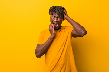 Young black man wearing rastas over yellow background whining and crying disconsolately.