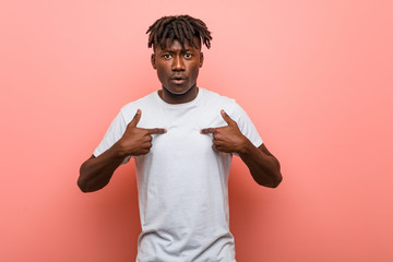 Young african black man surprised pointing at himself, smiling broadly.