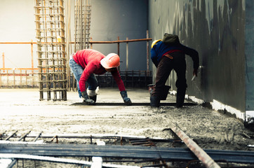 Construction worker troweling wet concrete on a top of concrete floor slab new construction site