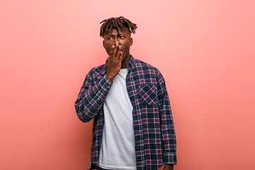 Young african black man yawning showing a tired gesture covering mouth with him hand.