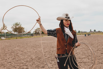 pretty Chinese cowgirl throwing the lasso in a horse paddock - obrazy, fototapety, plakaty