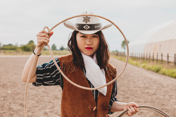 pretty Chinese cowgirl throwing the lasso in a horse paddock