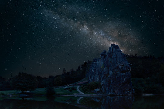 The impressive sandstone rocks of Externsteine in North Rhine Westphalia in Germany at a dark night with the milky way in the background.