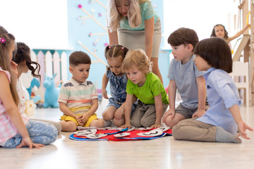 Group of kids learning time with clock toy in kindergarten - obrazy, fototapety, plakaty