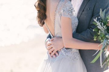 The groom in a suit hugs the bride in a wedding dress