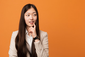 Young business chinese woman relaxed thinking about something looking at a copy space.