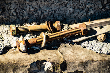 Very old rusty bolts, screws and nuts on dirty construction background. Concrete surface. Ancient metal tools after corrosion