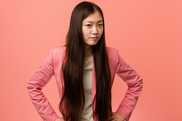 Young business chinese woman wearing pink suit scolding someone very angry.