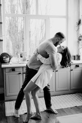 Romantic young couple cooking together in the kitchen. The girl in the white shirt. Breakfast together.