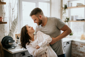 Obraz premium Romantic young couple cooking together in the kitchen. The girl in the white shirt. Breakfast together.