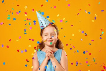 Cute little girl celebrates birthday. The child closed his eyes and makes a wish in the rain of...