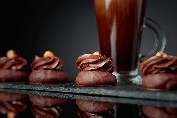  Chocolate dessert with hazelnut and coffee with cream on a black background.