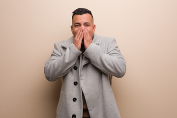 Young latin business man laughing about something, covering mouth with hands