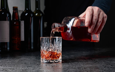 Barman pours whiskey in a glass at the bar.
