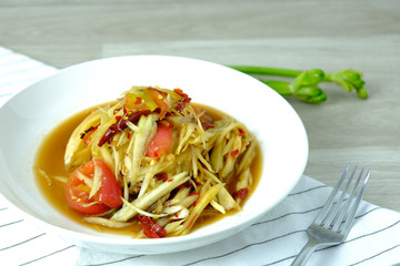 Papaya Salad with Crab. Thai food cuisine menu “Somtum”. It’s tasty, Spicy, Sour and Salty. Famous in Thailand and Lao. Close up Dish with fork on wooden background.