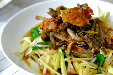 Papaya Salad with Crab. Thai food cuisine menu “Somtum”. It’s tasty, Spicy, Sour and Salty. Famous in Thailand and Lao. Close up Dish with fork on wooden background.