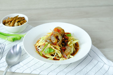 Papaya Salad with Shrimp. Thai food cuisine menu “Somtum”. It’s tasty, Spicy, Sour and Salty. Famous in Thailand and Lao. Close up Dish with fork on wooden background.