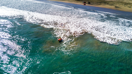 Rescue boat rushing to the shore on a local beach on sunny day. Muriwai Beach, Auckland, New Zealand